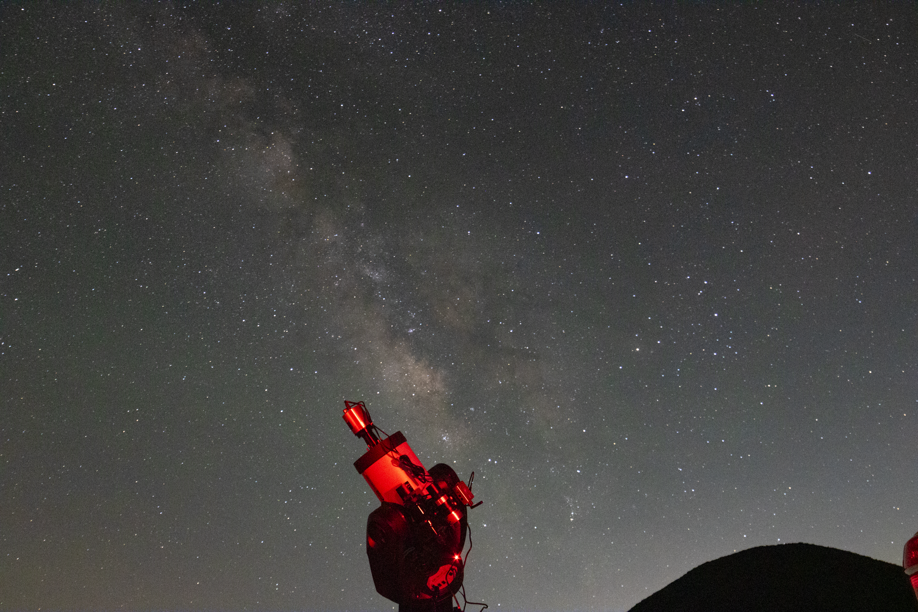 A single exposure image of Astroner'd advanced telescope with cameras in the foreground and the Milky Way galaxy in the background.